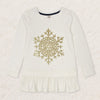 Young girl wearing a white long-sleeve top with a gold snowflake design on a plain background