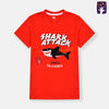 Two children wearing red 'Shark Attack' t-shirts on a beach.