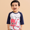 Child wearing a shirt with an octopus design and text on a beige background