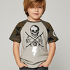 Child wearing a gray and green t-shirt with a skull design on a plain background