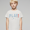 Young boy wearing a gray t-shirt with 'PLAY' printed on it against a plain background