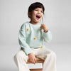 Child wearing a light blue sweater with daisy flowers, sitting on a small wooden stool against a plain background.
