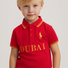 Child wearing a red polo shirt with 'Dubai' printed on it against a plain background