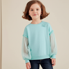 Child wearing a light blue sweater with sheer sleeves on a beige background