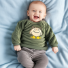 Baby wearing a green sweater with a cartoon design on a blue blanket