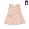 Baby wearing an orange and white striped dress sitting on a soft surface
