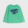 Young girl wearing a teal long-sleeve shirt with a heart design on a beige background