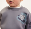 Child wearing a sweatshirt with a logo in a snowy mountain landscape
