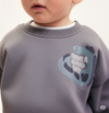 Child wearing a sweatshirt with a logo in a snowy mountain landscape