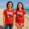 Two children wearing red 'Shark Attack' t-shirts on a beach.