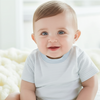 Baby wearing a striped shirt sitting on a soft, light-colored surface.