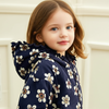 Young girl wearing a navy blue floral-patterned dress against a light background